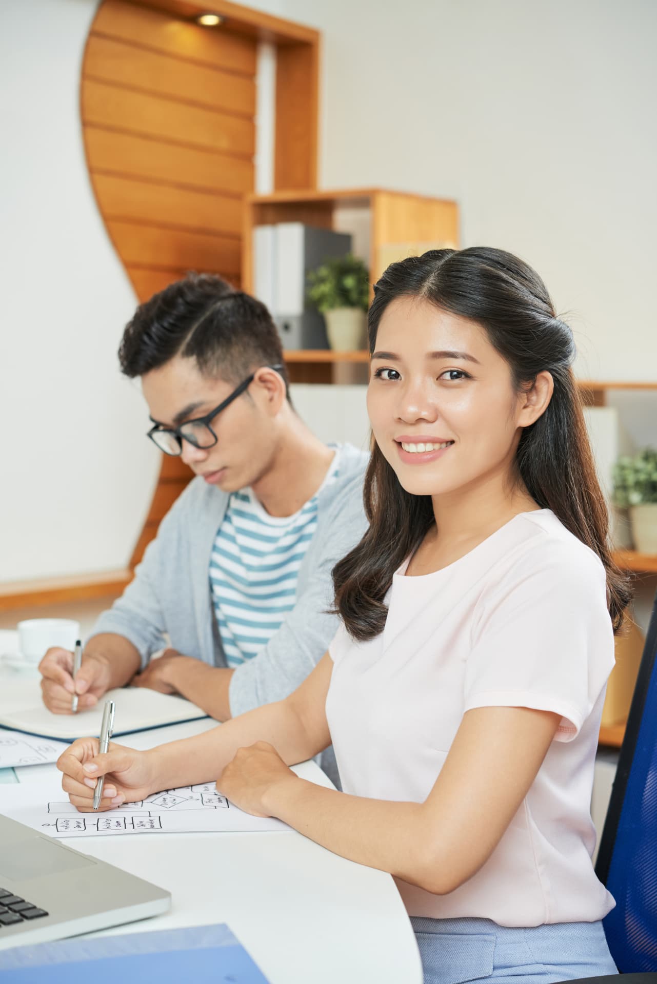 Two colleagues going over notes together at a desk